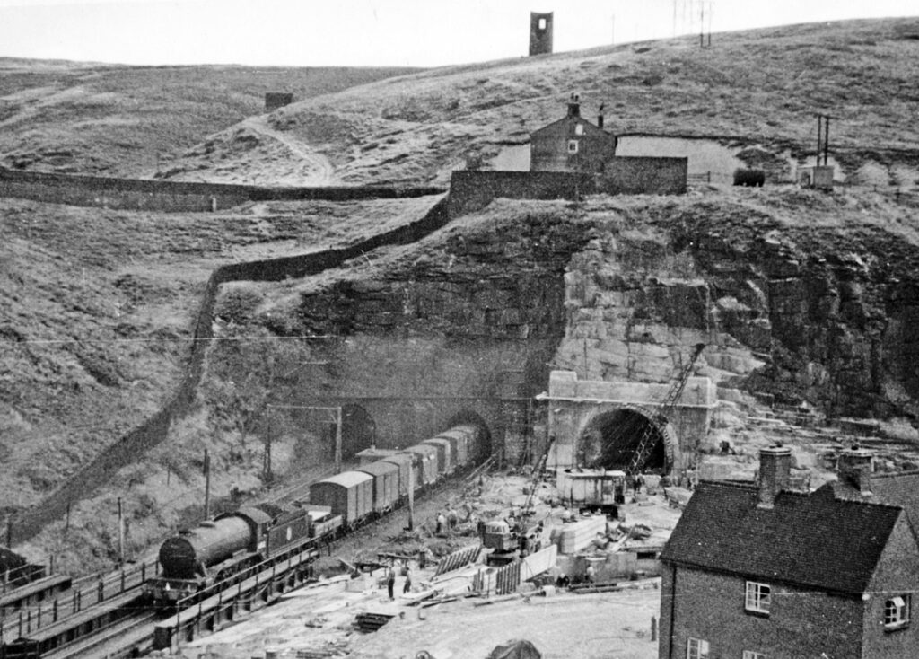 The west portal of Woodhead Tunnel on Joseph Locke’s Manchester-Sheffield (Woodhead) line in 1953, showing the two Victorian single-track tunnels and construction work on the double-track replacement, now also closed
